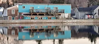 a blue house next to a body of water at Campbellford Studio Apt 4 in Campbellford