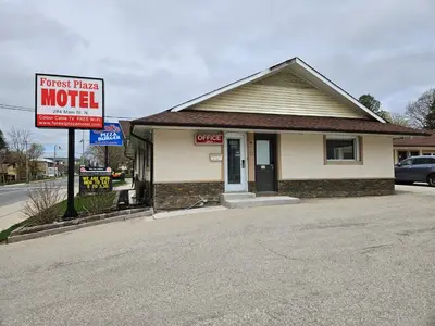 a house with a motel sign in front of it at Forest Plaza Motel in Mount Forest