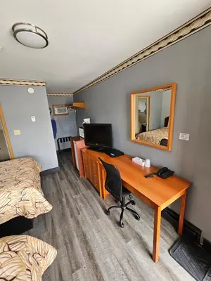 a bedroom with a desk and a bed and a mirror at Forest Plaza Motel in Mount Forest
