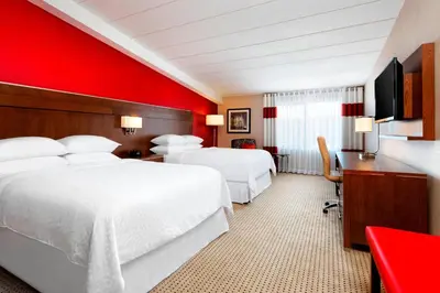 a hotel room with two beds and a red wall at Four Points by Sheraton London in London