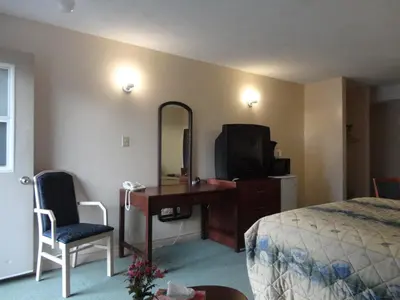 a hotel room with a bed and a desk and a television at Good Night Inn in Port Colborne