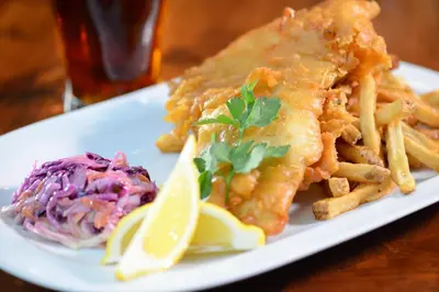 a plate of food with fish and fries and lemon slices at Jordan House Hotel in Jordan
