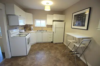 a small kitchen with white appliances and a table at Maison Doucet in Niagara Falls