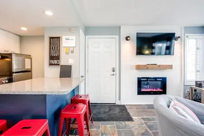 a kitchen with a bar with a fireplace and red stools at Blue Mountain (1 bedroom) Escape at North Creek Resort in Blue Mountains
