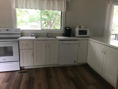 a kitchen with white cabinets and a sink and a window at Beachside on Lake Muskoka in Port Carling