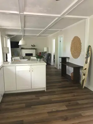 a kitchen and living room with white cabinets and wood floors at Beachside on Lake Muskoka in Port Carling