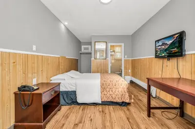 a bedroom with a bed and a desk and a television at Park Motel in Toronto