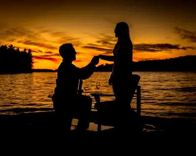 a man and woman sitting on the beach at sunset at Sherwood Inn in Port Carling