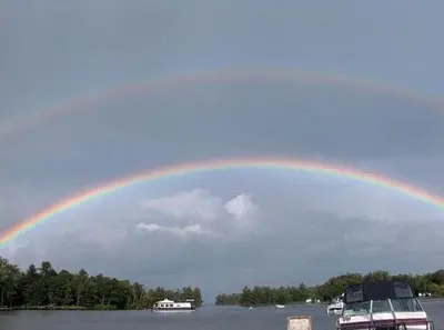 a rainbow in the sky over a lake with boats at Sunrise Resort in Buckhorn