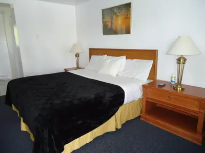 a bedroom with a large bed and a table with lamps at Westmount Motel in Woodstock