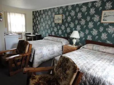 a bedroom with two beds and two chairs at Hipwell's Motel in Fonthill