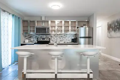 a kitchen with a large kitchen island with bar stools at ENTIRE 2 BEDROOM APARTMENT UPTOWN WATERLOO - e2 in Waterloo