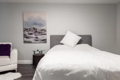 a bedroom with a white bed and a chair at ENTIRE BACHELOR UNIT EN-SUITE UPTOWN WATERLOO - e5 in Waterloo
