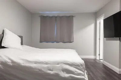 a bedroom with a white bed and a television at ENTIRE BACHELOR UNIT EN-SUITE UPTOWN WATERLOO - e5 in Waterloo