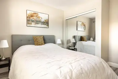 a bedroom with a large white bed and a mirror at ENTIRE 2 BEDROOM APARTMENT DOWNTOWN - u3 in Waterloo
