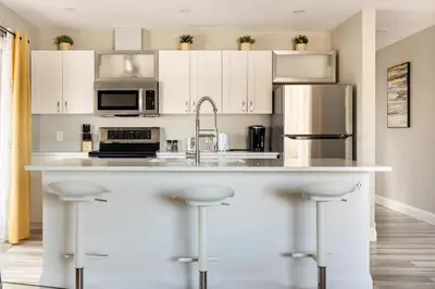 a kitchen with white cabinets and a kitchen island with bar stools at ENTIRE 2 BEDROOM APARTMENT DOWNTOWN - u3 in Waterloo