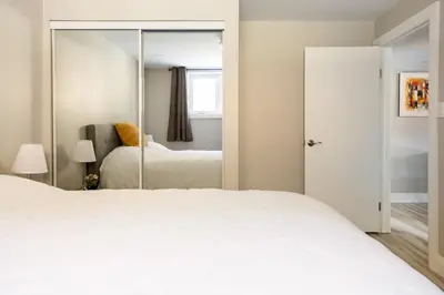 a bedroom with a white bed and a mirror at ENTIRE 2 BEDROOM APARTMENT DOWNTOWN - u1 in Kitchener