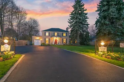 a house with a driveway in front of a sunset at Abacot Hall Bed & Breakfast in Niagara on the Lake