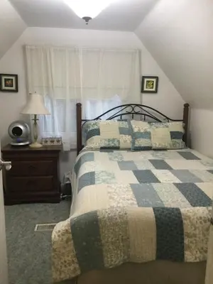 a bedroom with a bed with a blue and white quilt at Burley's Executive Garden Suite in Peterborough