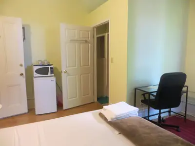 a room with a microwave and a table and a chair at Keppner Guesthouse in Toronto