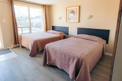 a hotel room with two beds and a window at Clarkson Village Motel, 1815 Lakeshore Rd West Mississauga in Mississauga