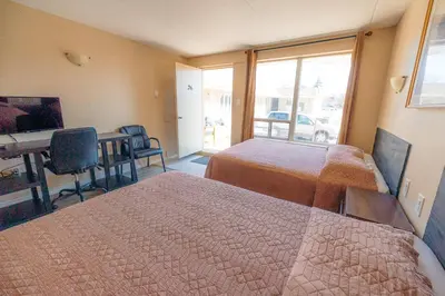 a hotel room with two beds and a desk and a table at Clarkson Village Motel, 1815 Lakeshore Rd West Mississauga in Mississauga