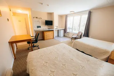 a hotel room with two beds and a desk at Clarkson Village Motel, 1815 Lakeshore Rd West Mississauga in Mississauga