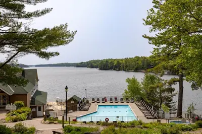 a swimming pool with a view of a lake at Rocky Crest Golf Resort in MacTier