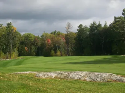 a green golf course with a rock in the grass at Rocky Crest Golf Resort in MacTier