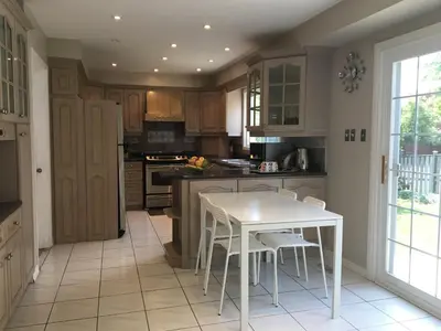 a kitchen with a white table and white chairs at Comfort Stays near Toronto Airport in Mississauga