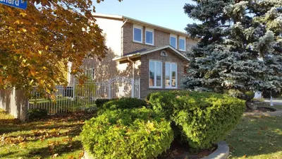 a house with bushes in front of a yard at Comfort Rooms Near Toronto Airport in Mississauga