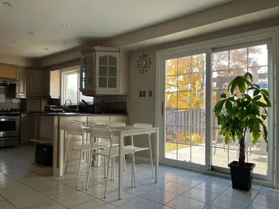 a kitchen with white chairs and a table with a potted plant at Comfort Rooms Near Toronto Airport in Mississauga