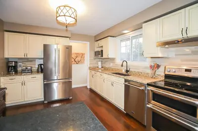 a kitchen with white cabinets and a stainless steel refrigerator at Dorchester Cottage Licence 044-2022 in Niagara on the Lake