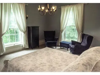 a bedroom with a bed and two chairs and windows at Culverdene House in Simcoe