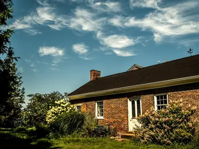 a brick house with a black roof and clouds in the sky at Culverdene House in Simcoe