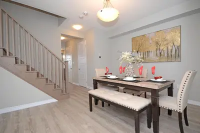 a dining room with a table and chairs and a staircase at Royal Stays Townhome Collection - 3 Bedroom Townhome in Oakville in Oakville