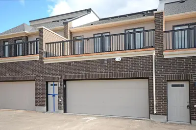 a brick apartment building with two garage doors at Royal Stays Townhome Collection - 3 Bedroom Townhome in Oakville in Oakville