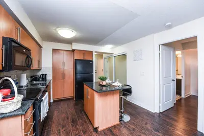 a kitchen with wooden cabinets and a black refrigerator at PlanURstay - Luxury Suites Mississauga Downtown in Mississauga