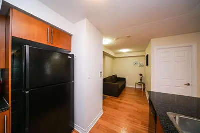a kitchen with a black refrigerator and a living room at PlanURstay - Luxury Suites Mississauga Downtown in Mississauga