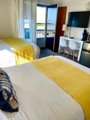 a hotel room with two beds and a desk at Paradise Inn On the Beach in Port Elgin
