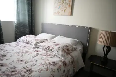a bedroom with a bed with a flowered blanket and a lamp at Metropolitan Suite in Niagara Falls