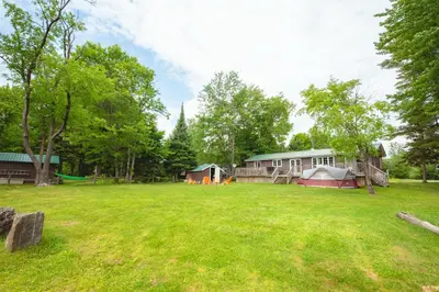 a large yard with a house and tents at Beautiful 3 Bdrm + Bunkie Waterfront Cottage Near Gull Lake in Minden