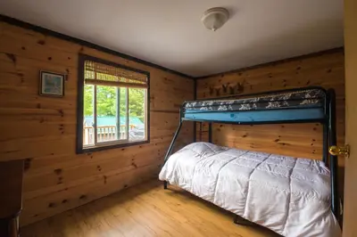 a bedroom with a bunk bed in a log cabin at Beautiful 3 Bdrm + Bunkie Waterfront Cottage Near Gull Lake in Minden