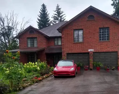 a red car parked in front of a brick house at Luxury Suites at Military Trail in Toronto