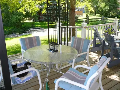 a table and chairs on a porch with a cat laying on it at Gables Bed & Breakfast in Stayner