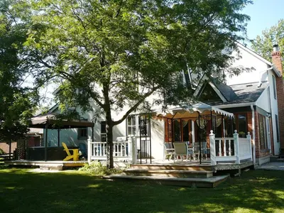 a white house with a porch and a tree at Gables Bed & Breakfast in Stayner