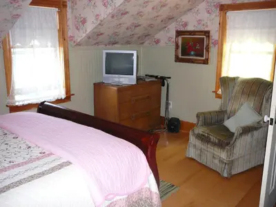 a bedroom with a bed and a tv and a chair at Gables Bed & Breakfast in Stayner