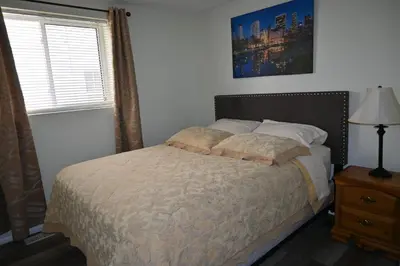 a bedroom with a bed and a lamp and a window at Oasis Suite in Niagara Falls