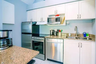 a kitchen with white cabinets and stainless steel appliances at Gorgeous Loft in the Heart of Blue Mountain in Blue Mountains