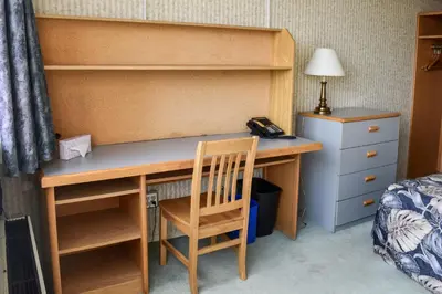 a desk in a bedroom with a bed and a telephone at Toronto Metropolitan University-International Living Learning Residence in Toronto